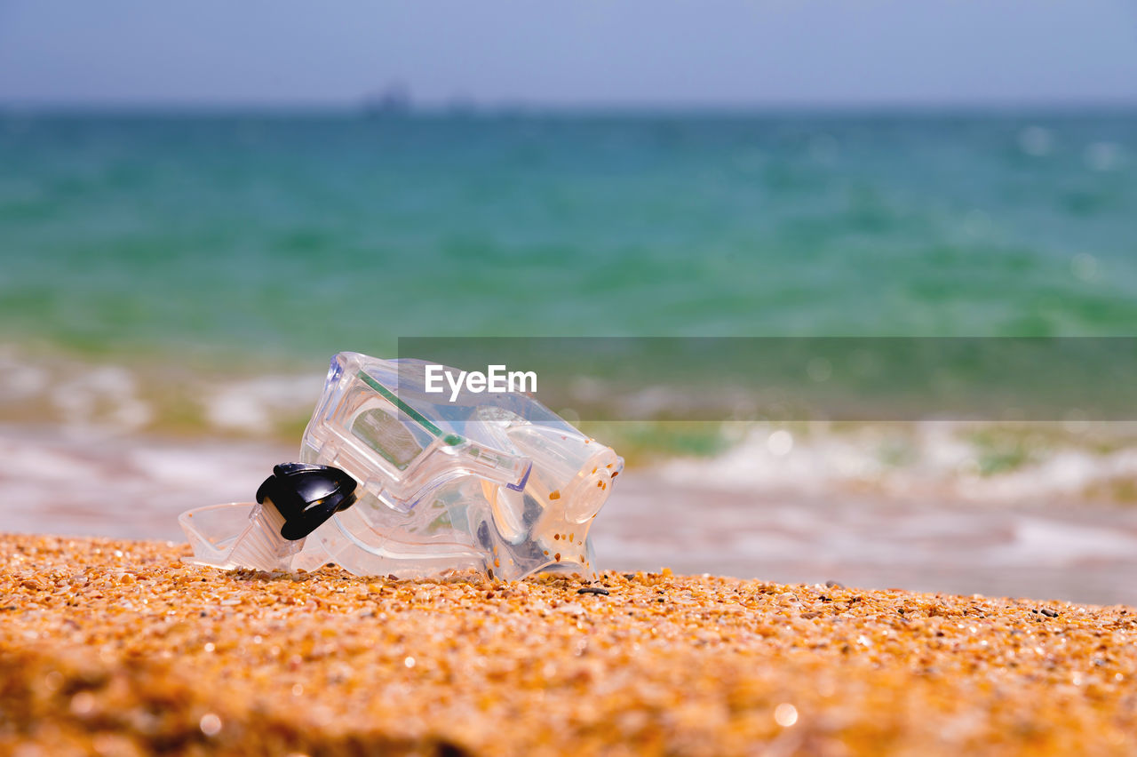 Shallow depth of field snorkeling mask lies on a sandy beach overlooking the sea and sky, no people