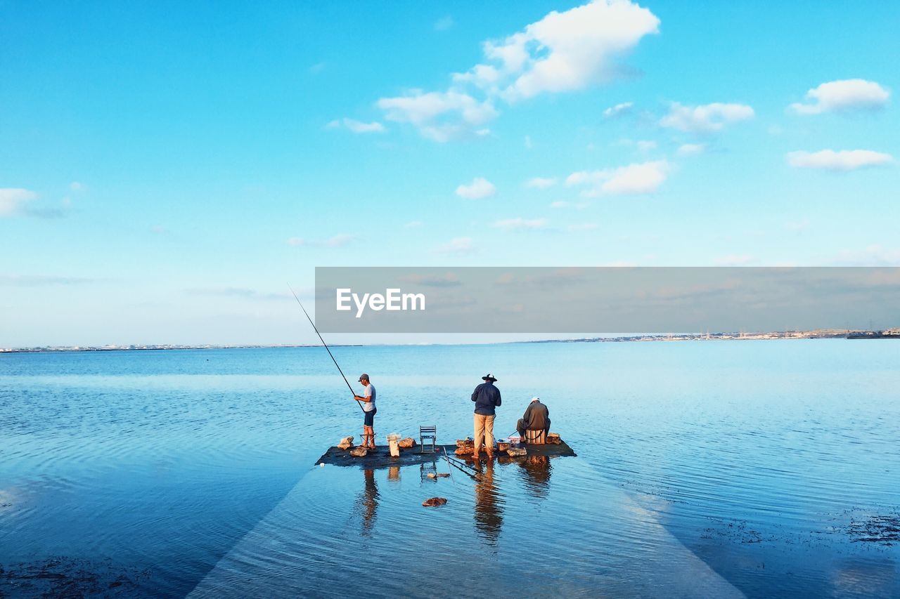 Men fishing at pier against sea