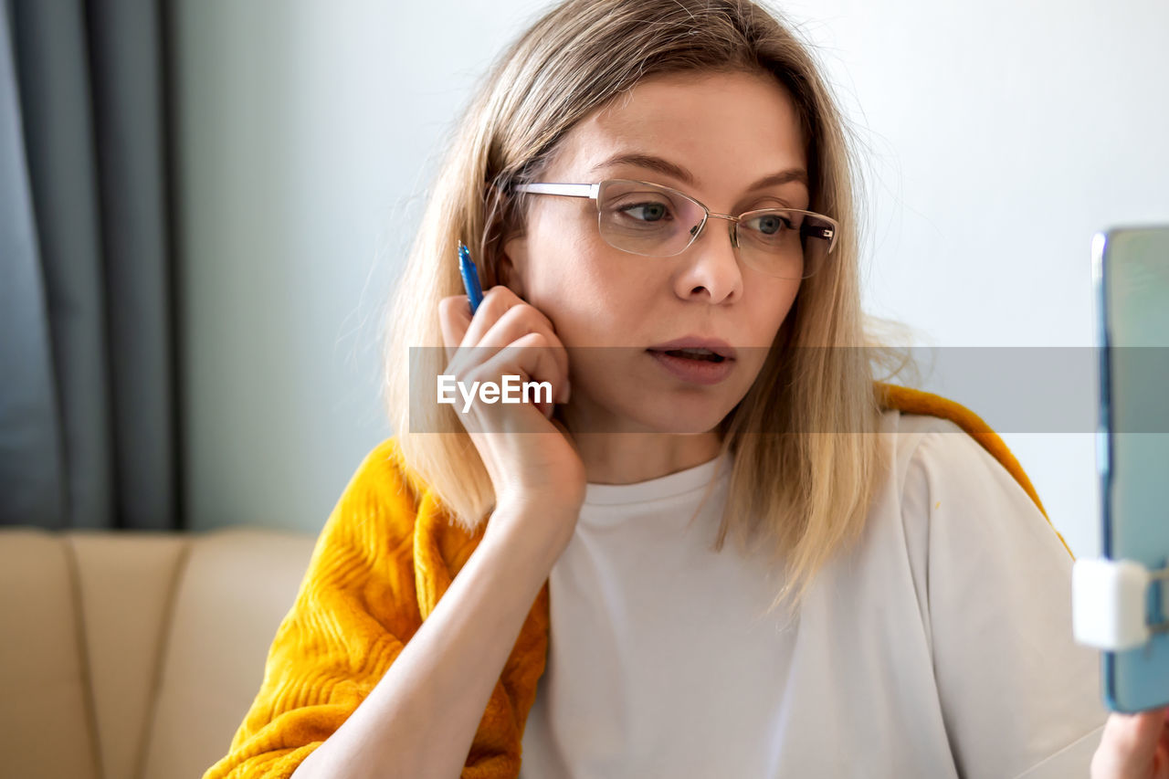 Woman in glasses talking online using mobile phone