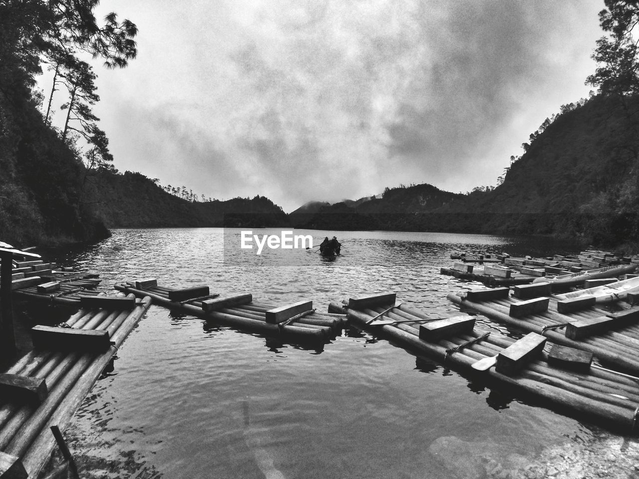 Wooden rafts in lake against cloudy sky