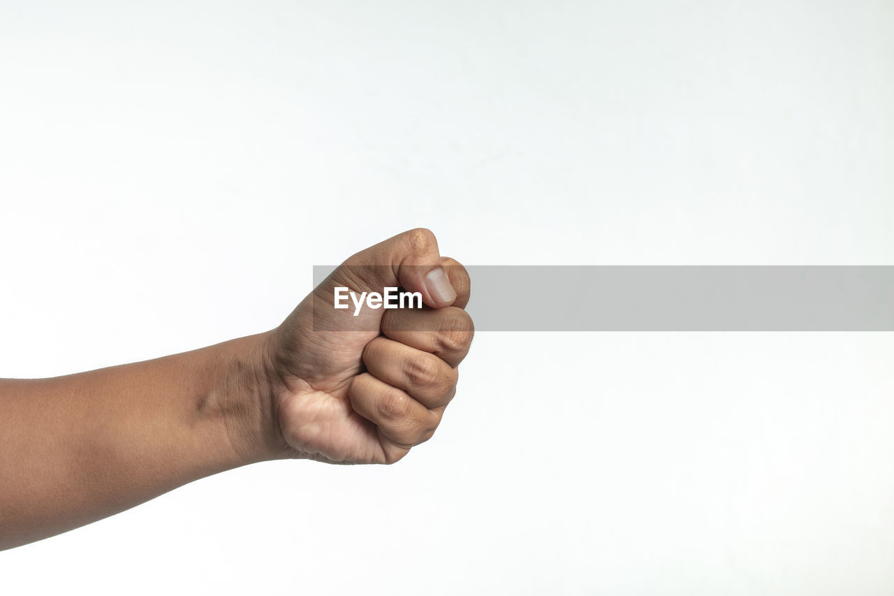 Cropped image of hand clinching fist against white background