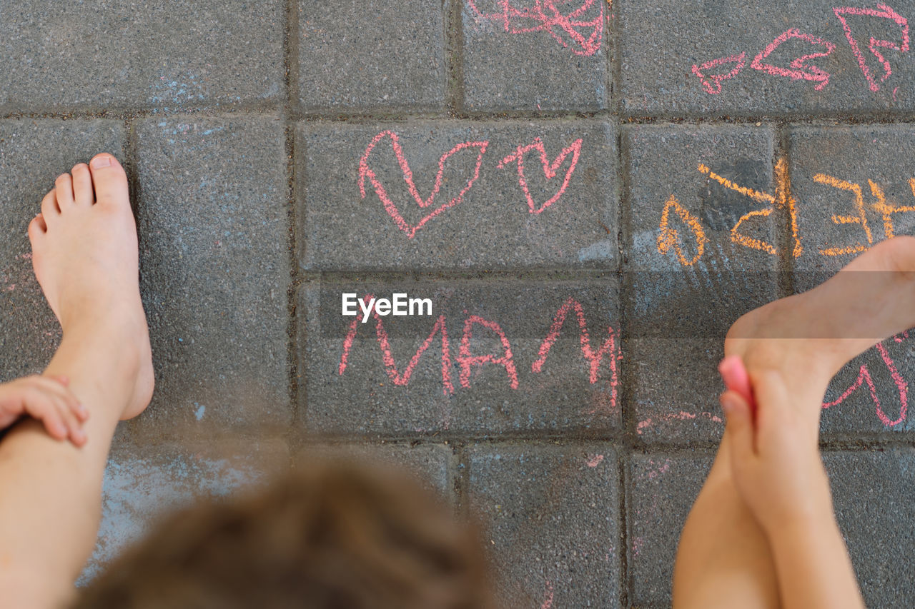 Cute boy draws the word mother with chalk. the boy loves his mother.