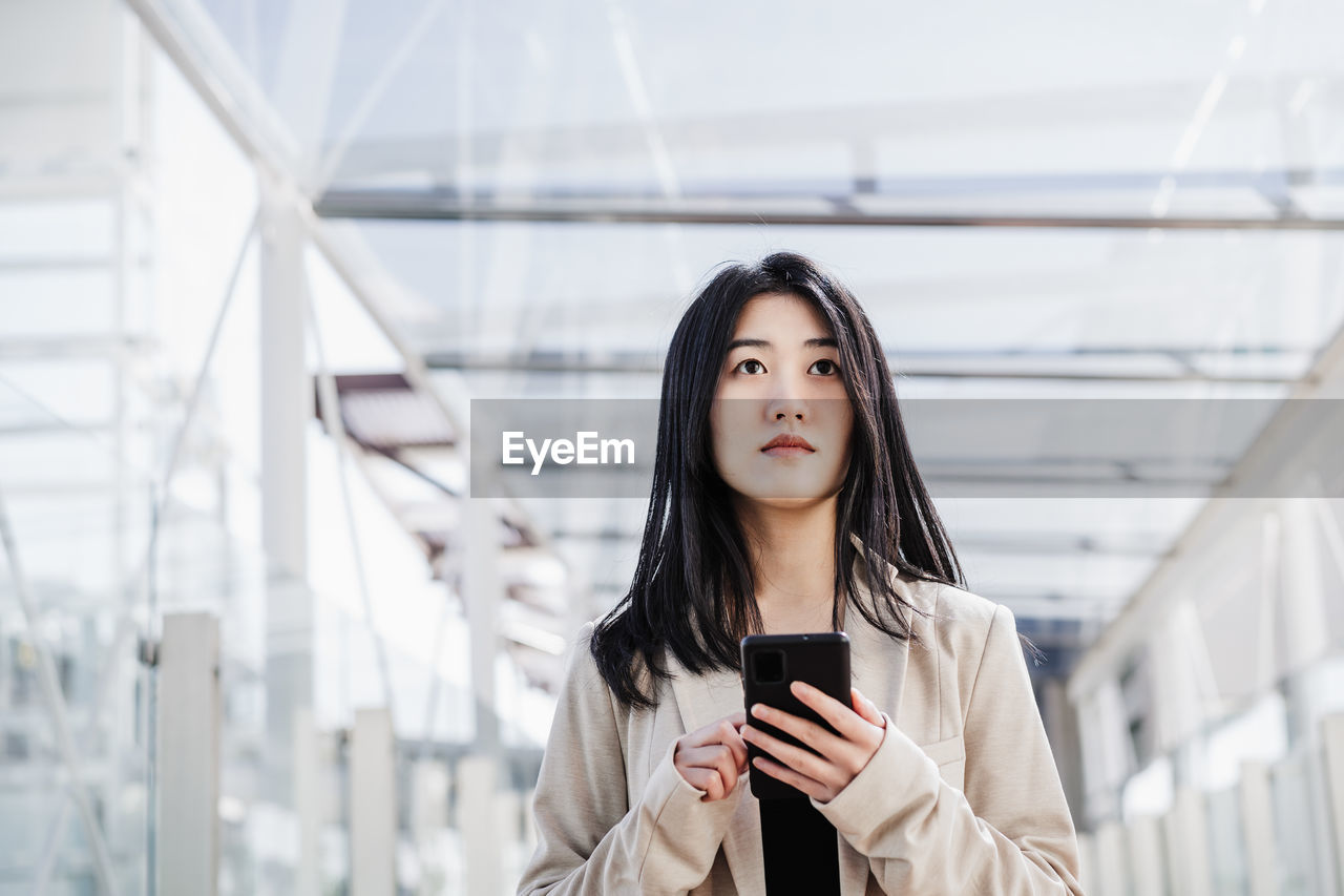 Portrait of beautiful chinese business woman using mobile phone in building office. technology