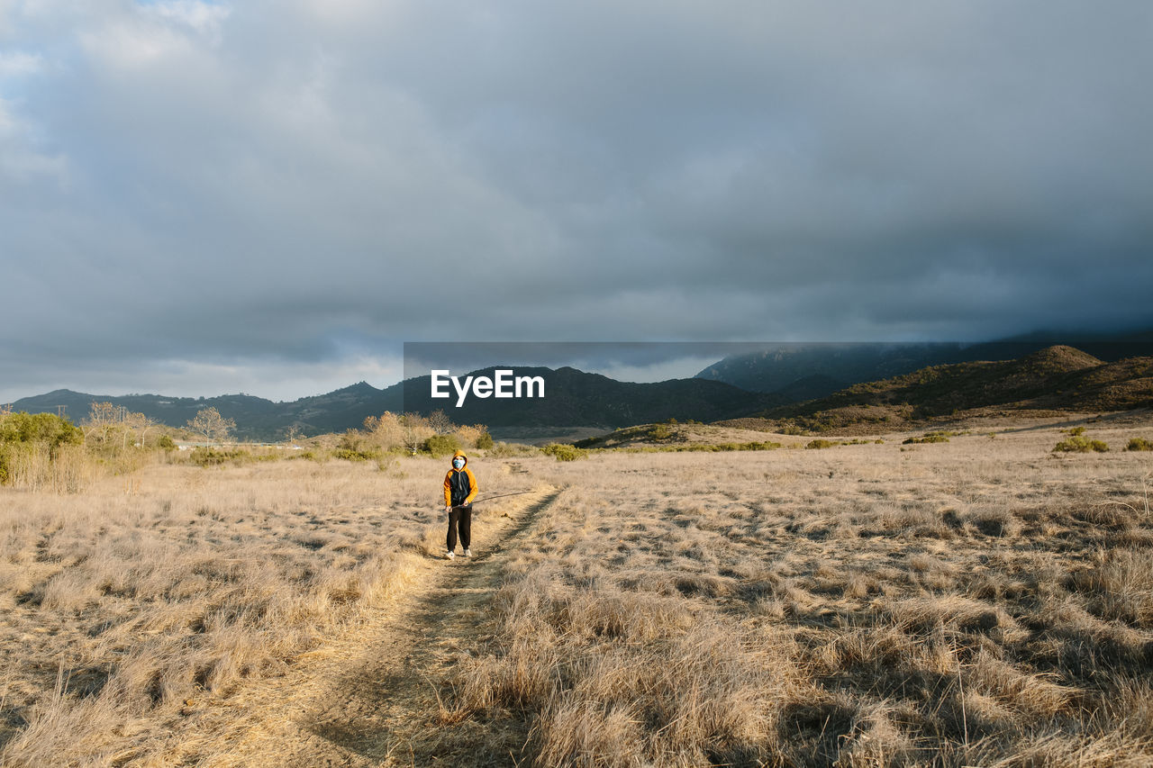 Boy walks on a nature trail in the sunshine as a storm rolls in