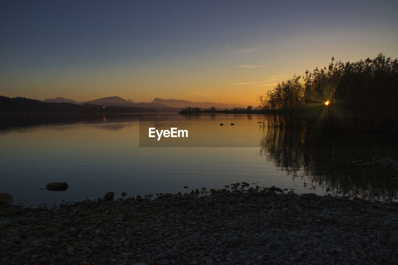 SCENIC VIEW OF LAKE AGAINST ORANGE SKY