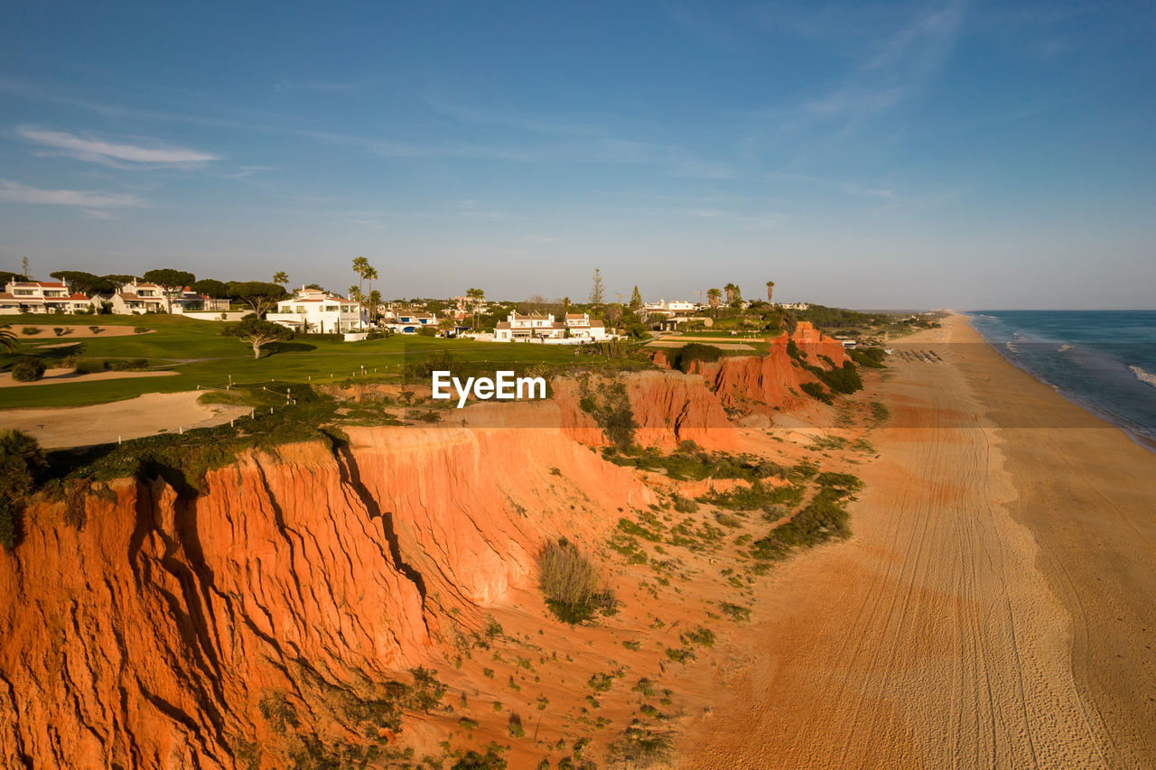 land, sky, water, sea, coast, beach, nature, scenics - nature, landscape, environment, sand, travel destinations, travel, beauty in nature, shore, horizon, terrain, tourism, architecture, cliff, ocean, no people, natural environment, cloud, outdoors, tranquility, coastline, sand dune, blue, horizon over water, plant, trip, holiday, vacation, sunset, tranquil scene, non-urban scene, building exterior, building, day, sunlight, built structure, panoramic, summer