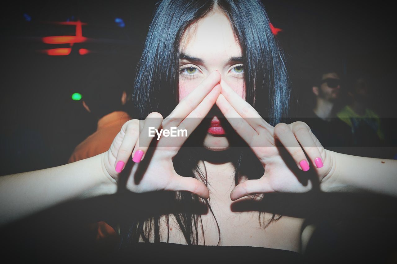 Portrait of beautiful woman gesturing while standing at nightclub