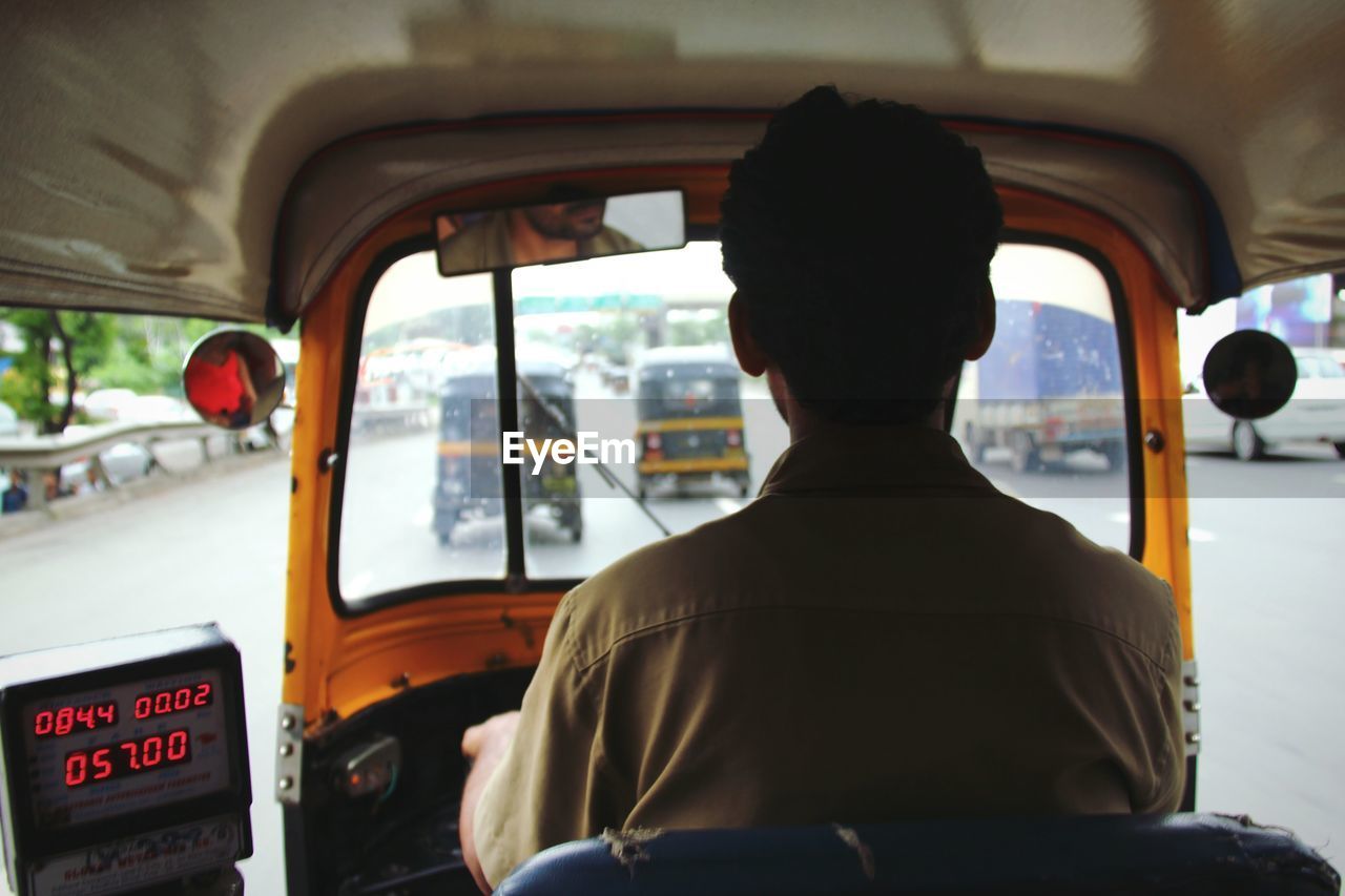 Rear view of driver driving rickshaw on street