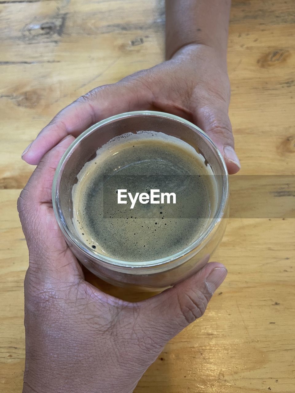 hand, food and drink, drink, refreshment, one person, holding, cup, high angle view, wood, freshness, mug, table, coffee, indoors, lifestyles, directly above, adult, food, coffee cup, close-up, hot drink, personal perspective