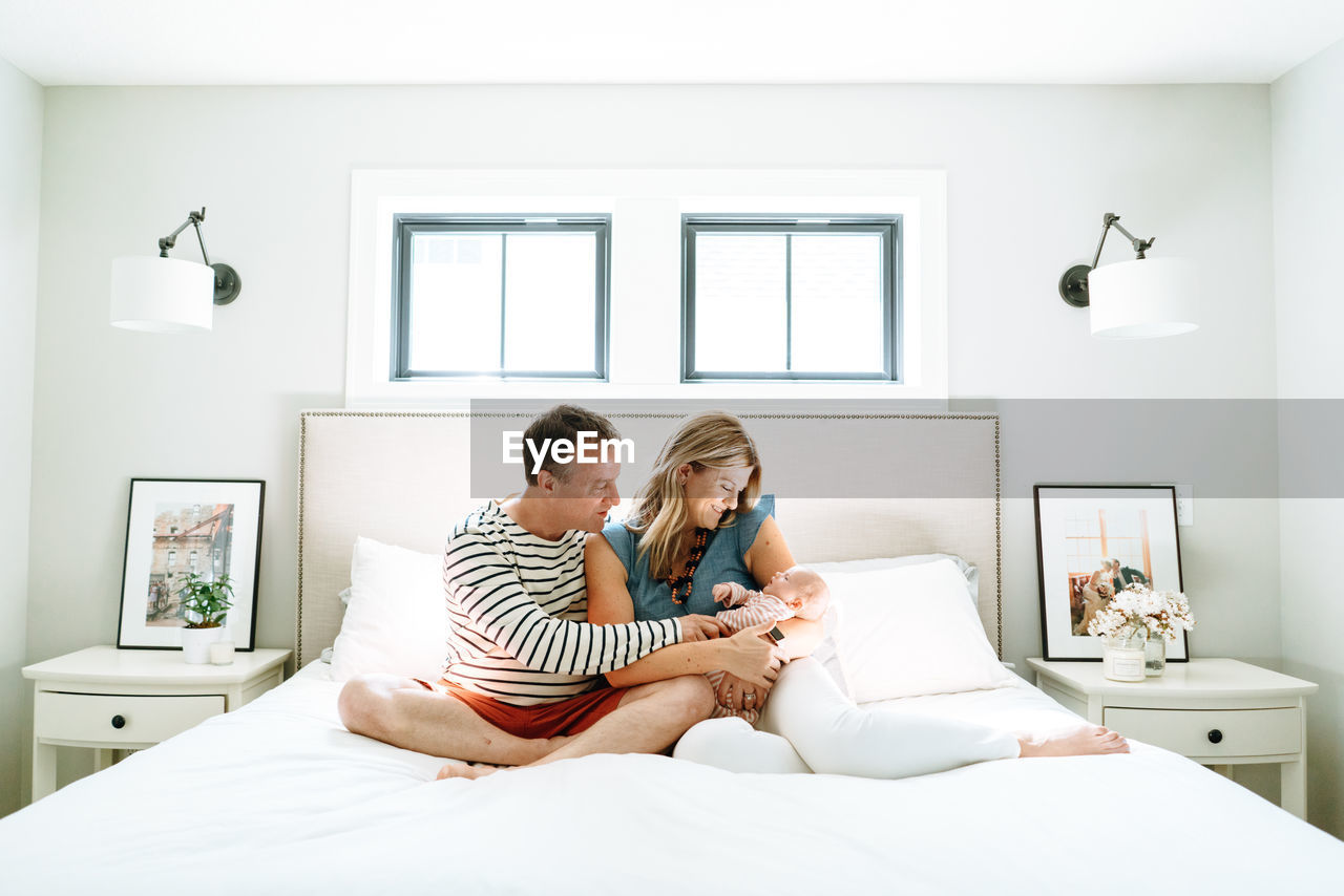 Straight on portrait of a mother and father holding their newborn girl