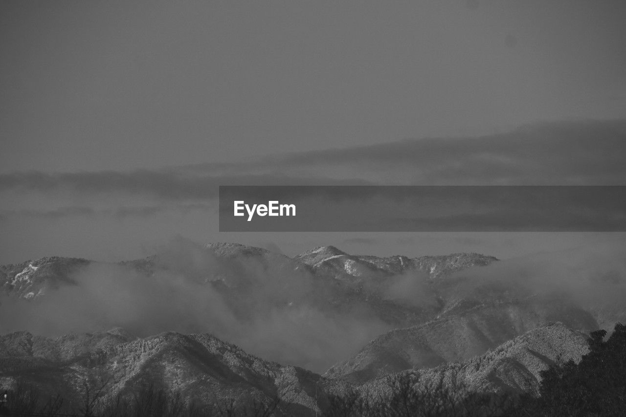 mountain, environment, scenics - nature, cloud, snow, landscape, mist, fog, sky, beauty in nature, black and white, darkness, mountain range, monochrome, nature, land, monochrome photography, tranquility, no people, dawn, winter, cold temperature, morning, tranquil scene, tree, horizon, travel, outdoors, non-urban scene, travel destinations, mountain peak, forest, plant, tourism, idyllic