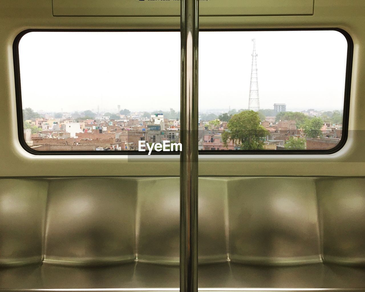 Close-up of cityscape against sky seen through train window