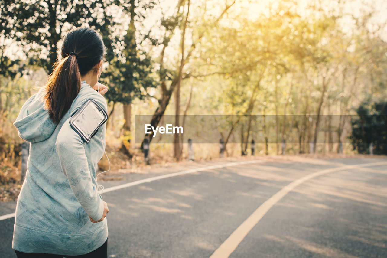 Woman running on road against trees