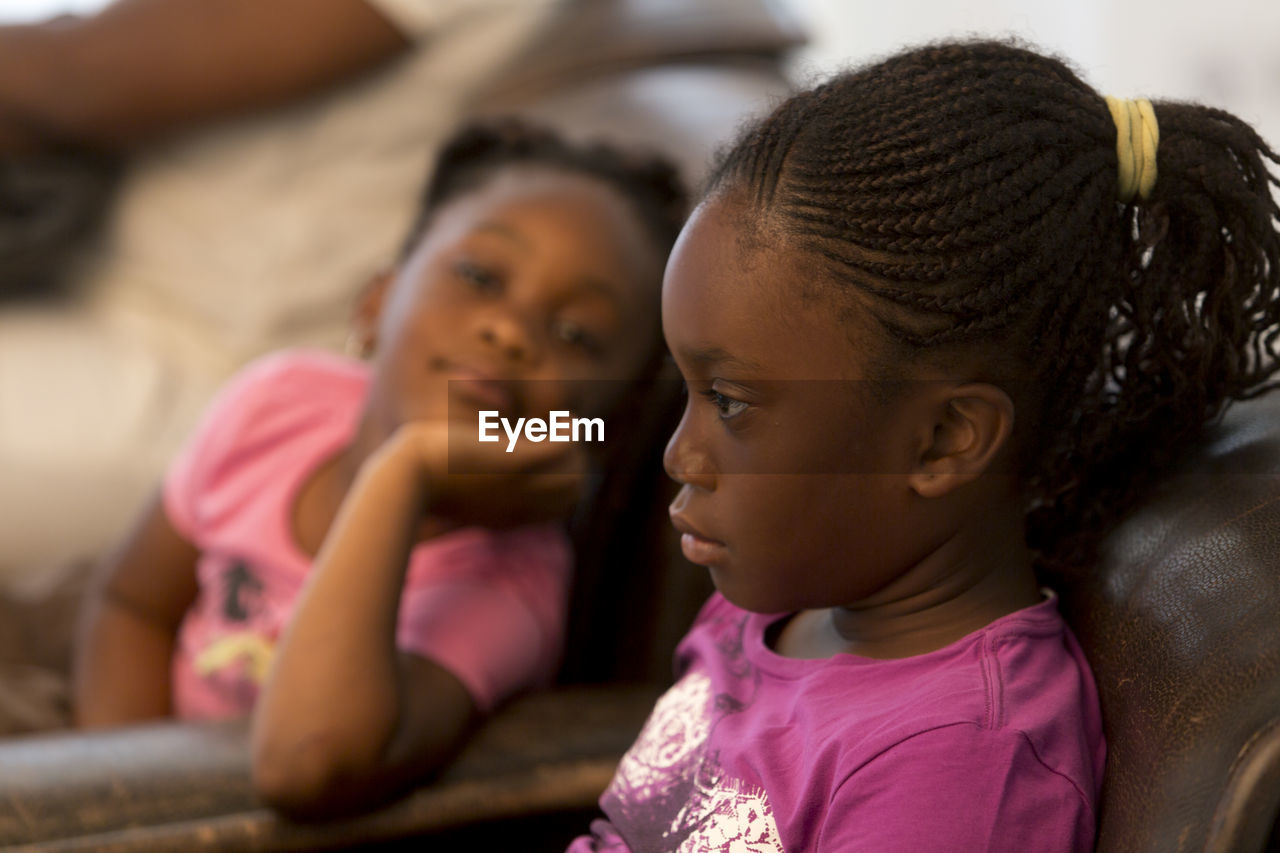 Close-up of girls sitting on sofa at home