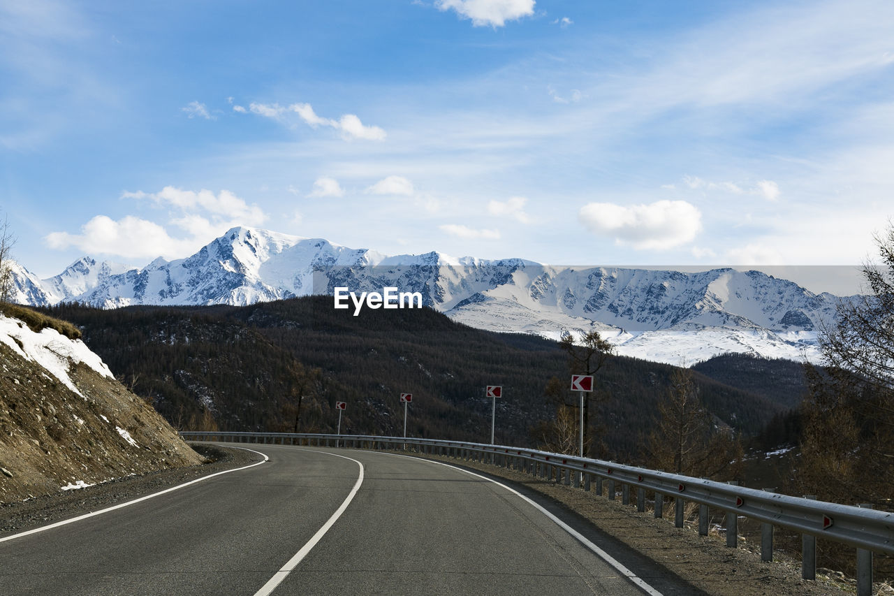 Road leading towards snowcapped mountains against sky