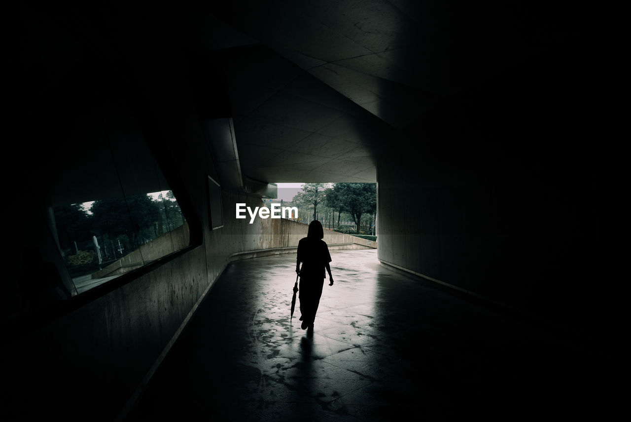 Rear view of woman walking under bridge