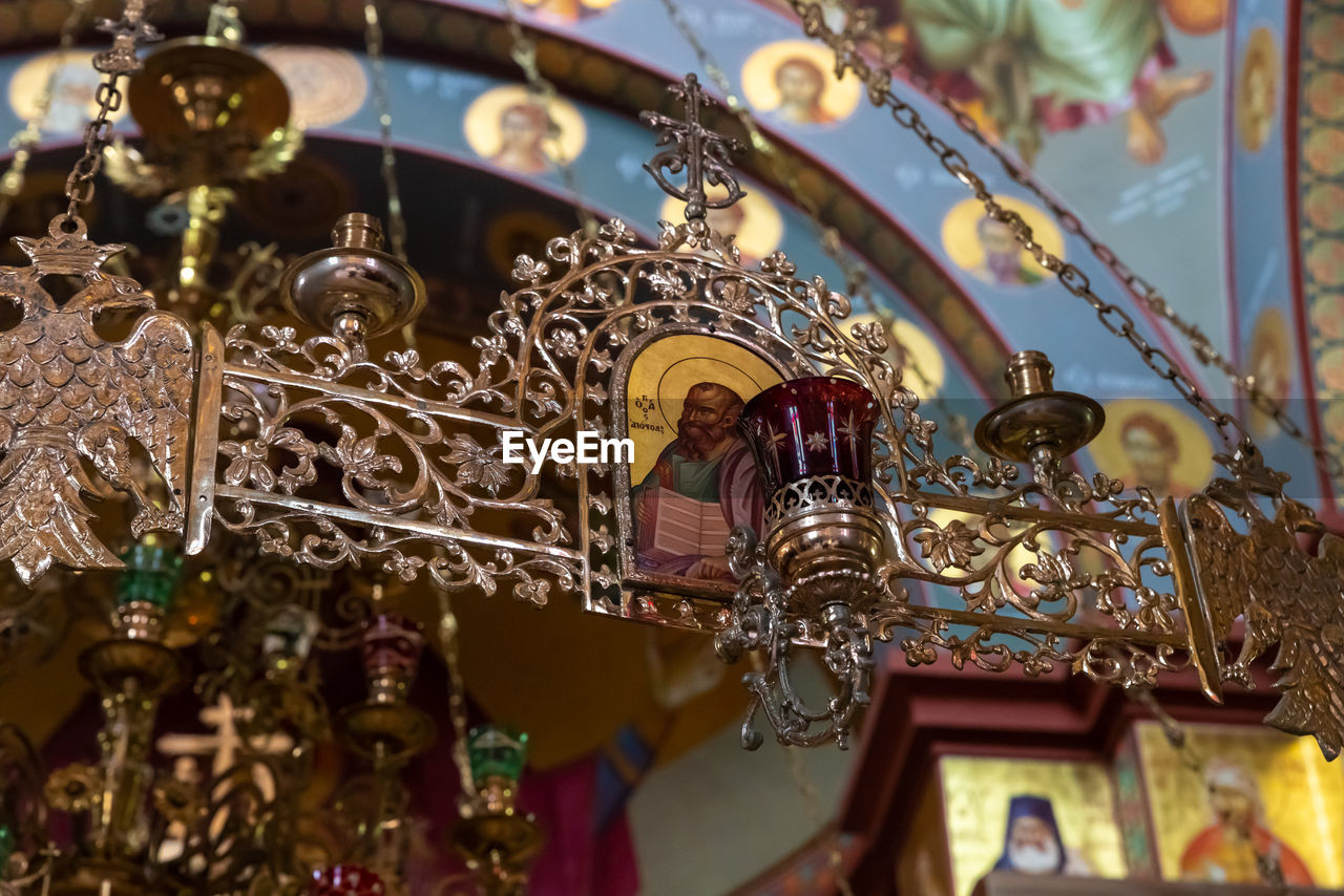 LOW ANGLE VIEW OF ILLUMINATED CHANDELIER HANGING ON CEILING IN TEMPLE