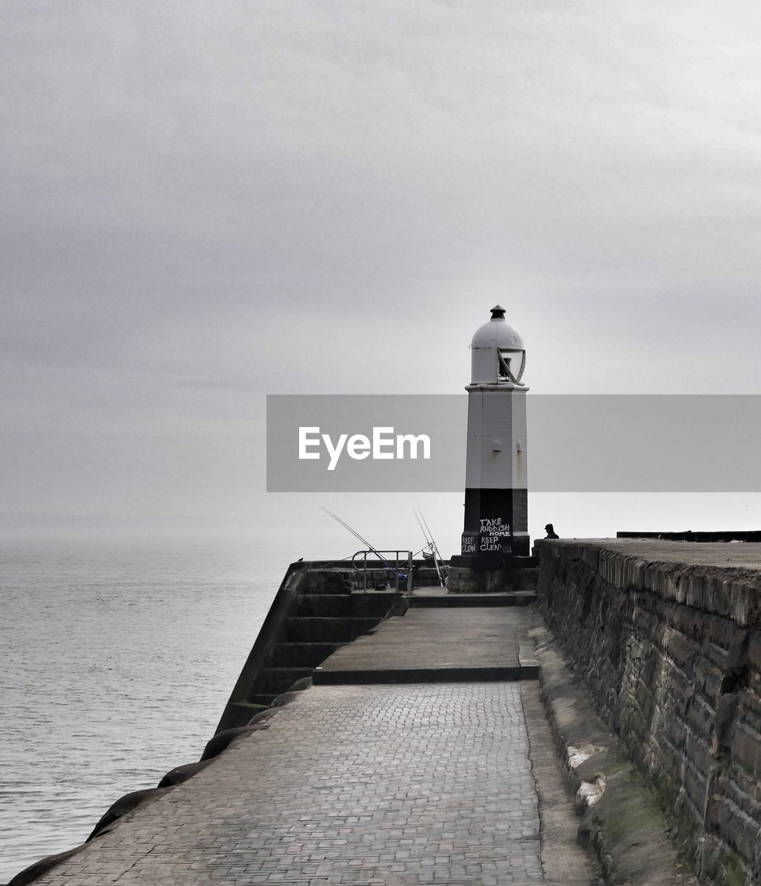 Lighthouse on calm sea against sky