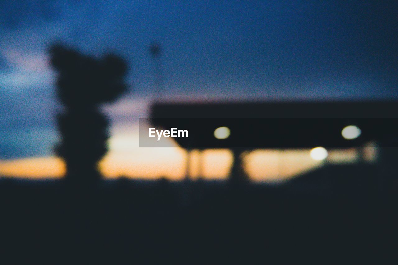 DEFOCUSED IMAGE OF ILLUMINATED LIGHTS AGAINST SKY