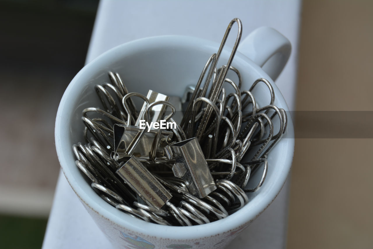 Portrait of a tiny cup filled with metal binder clips 