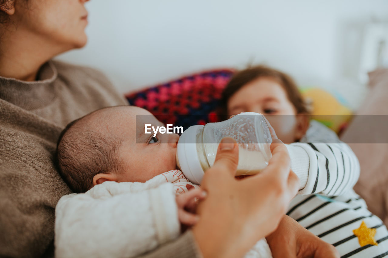 Close-up of mother feeding baby boy while sitting at home