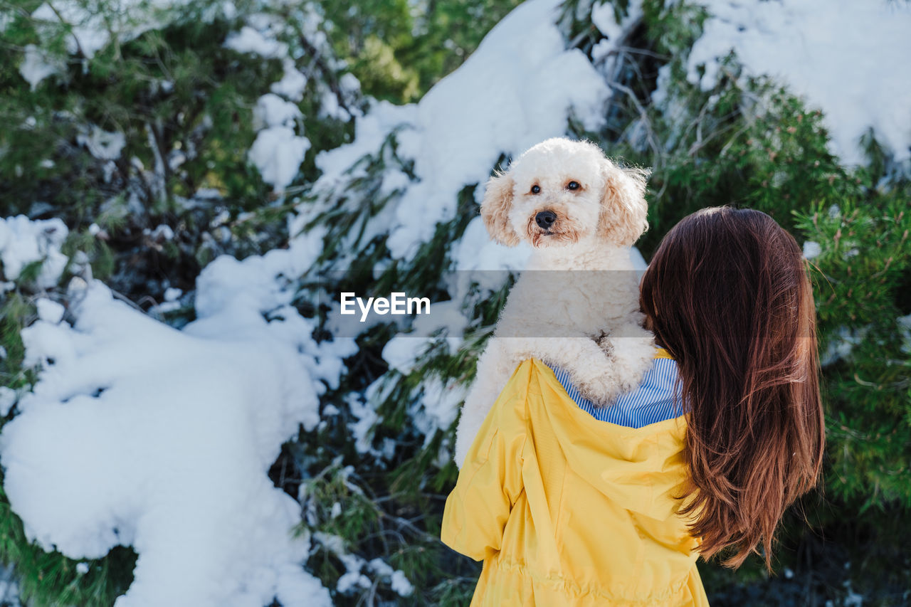 Woman with dog on snowcapped mountain against sky