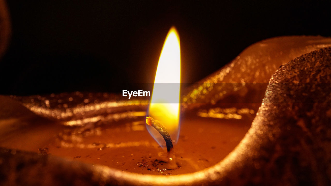 Close-up of lit candle in the dark