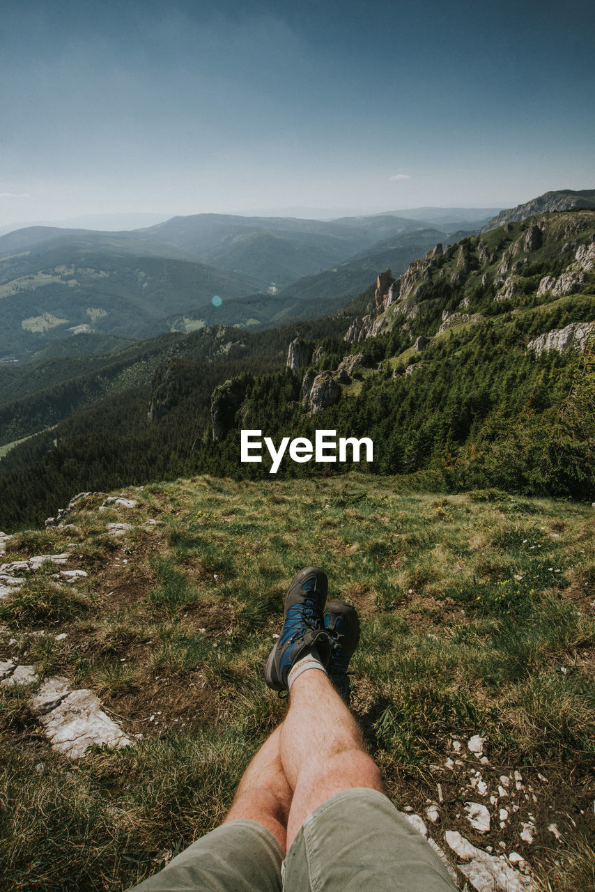 Low section of man on mountain against sky