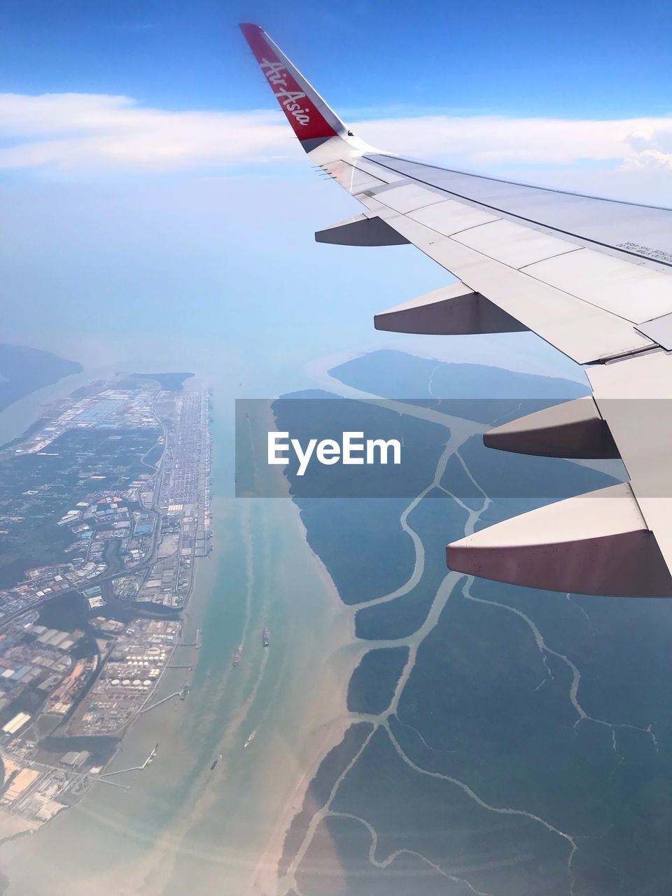 Aerial view of airplane flying over landscape against sky