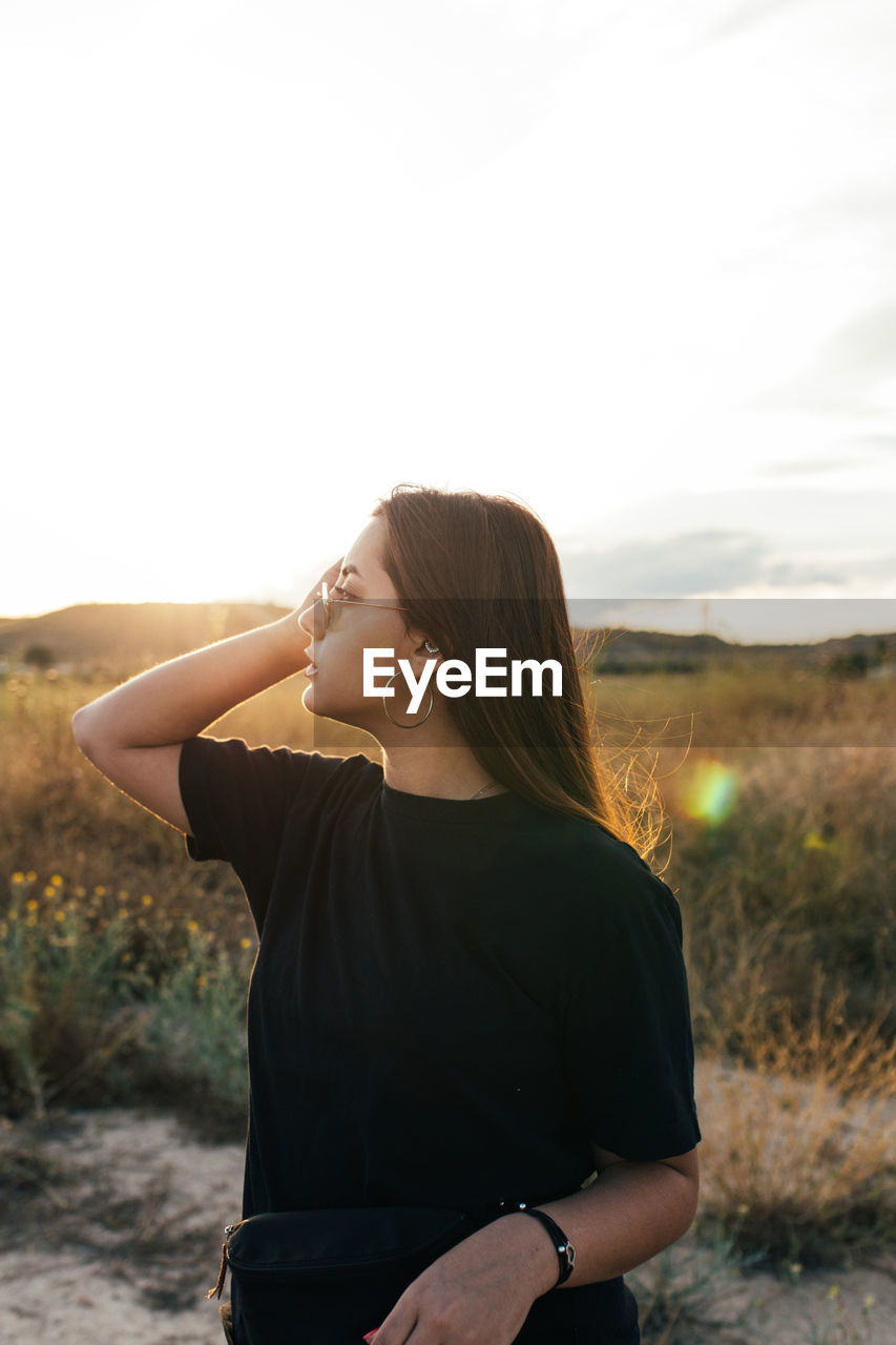 Teenager in sportswear and sunglasses watching the countryside sunset