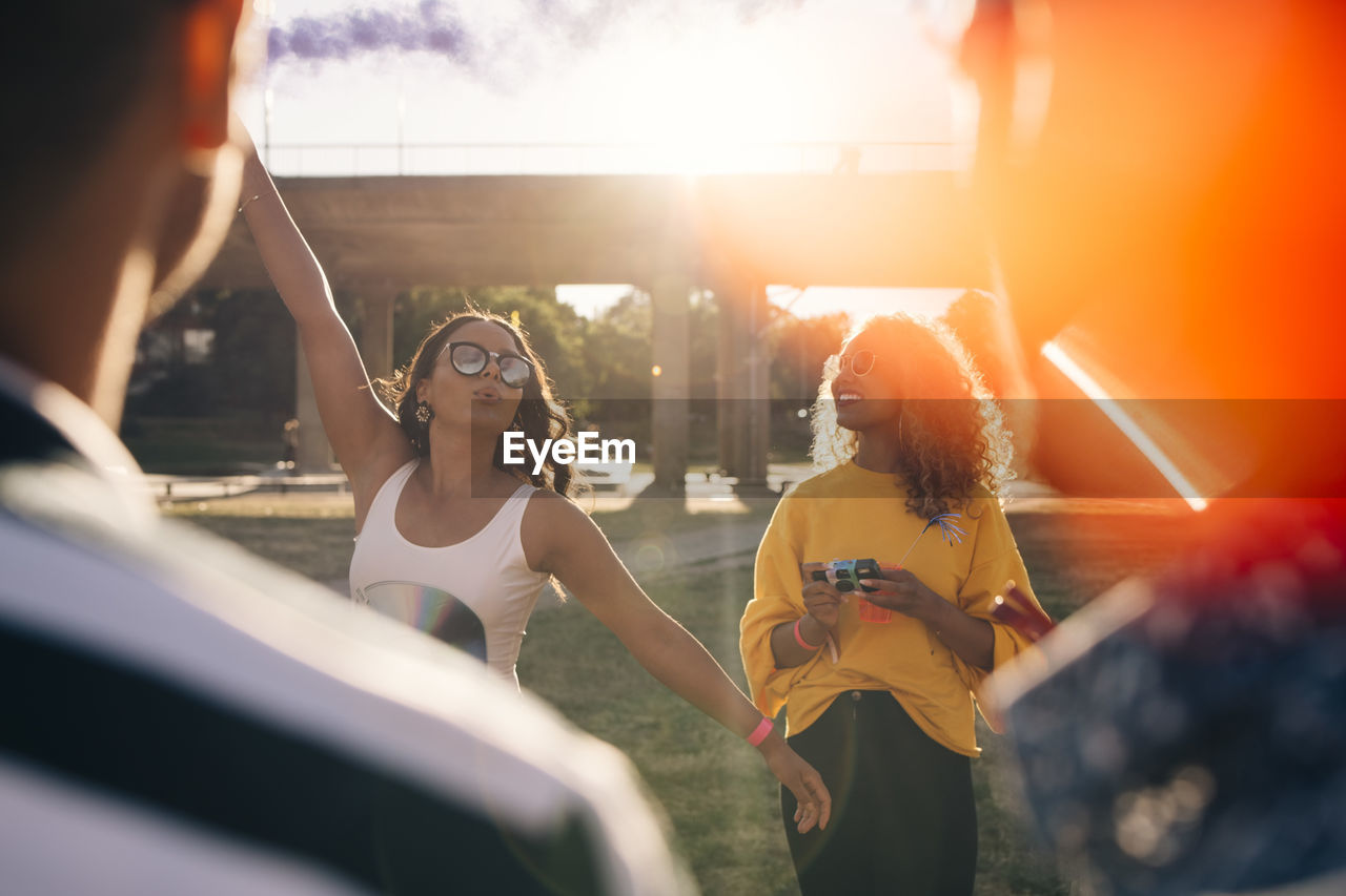 Playful woman having fun with friends during music festival on sunny day