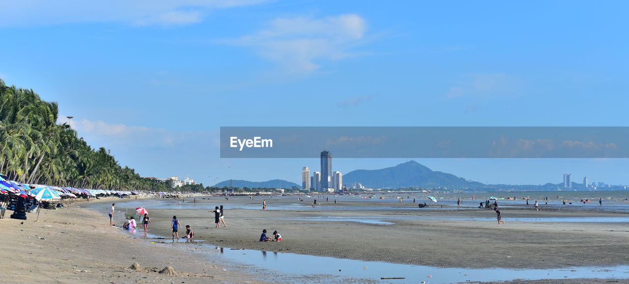body of water, water, land, beach, sky, sea, shore, coast, large group of people, nature, sand, travel destinations, holiday, crowd, group of people, vacation, travel, trip, ocean, tourism, cloud, architecture, bay, scenics - nature, beauty in nature, built structure, tourist, day, leisure activity, lifestyles, summer, outdoors, coastline, city, environment, blue, building exterior, mountain, walkway, water's edge, horizon, men
