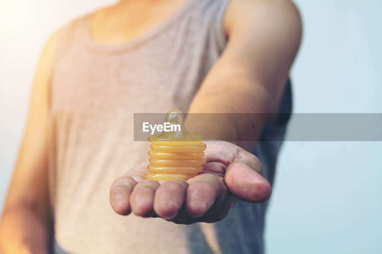 Midsection of man with condoms against sky