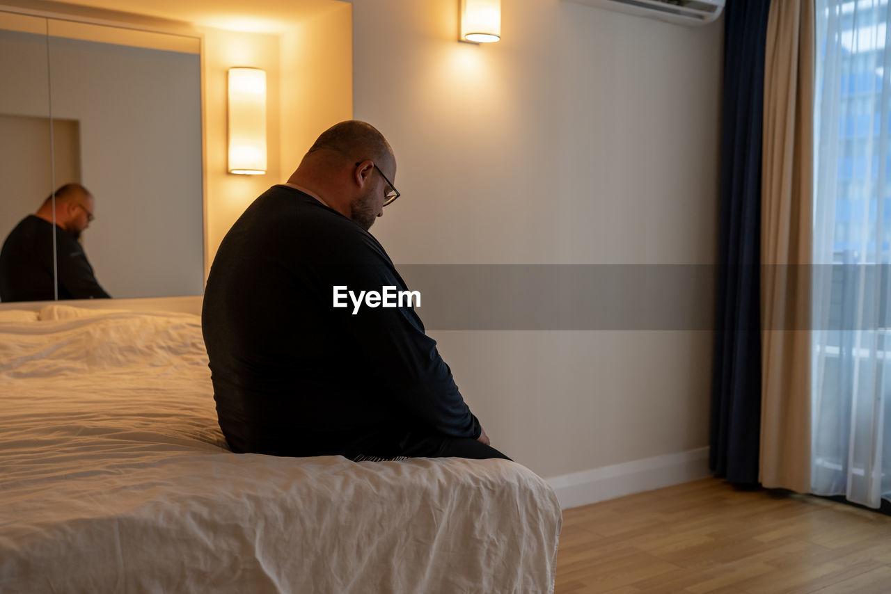 rear view of man looking through window at home