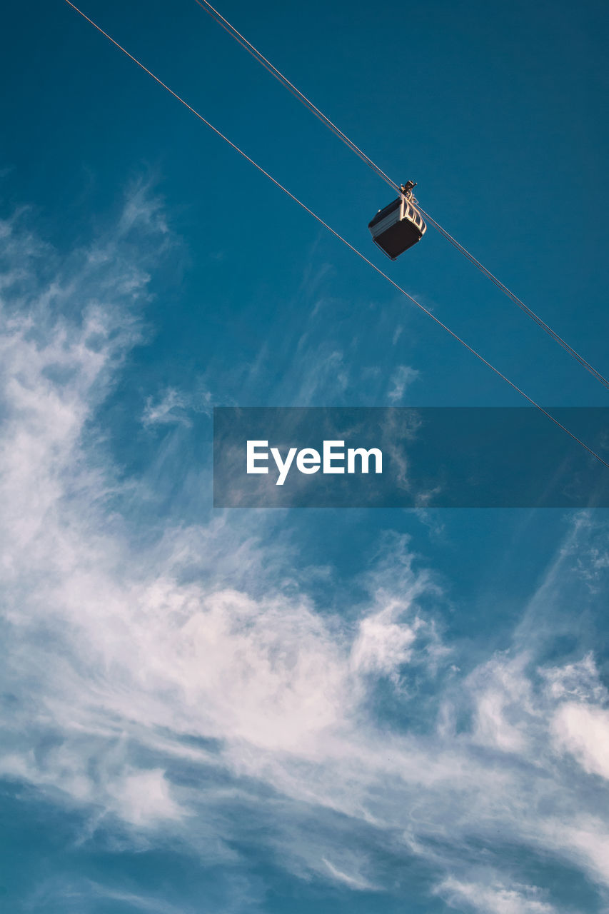Low angle view of ski lift hanging against sky
