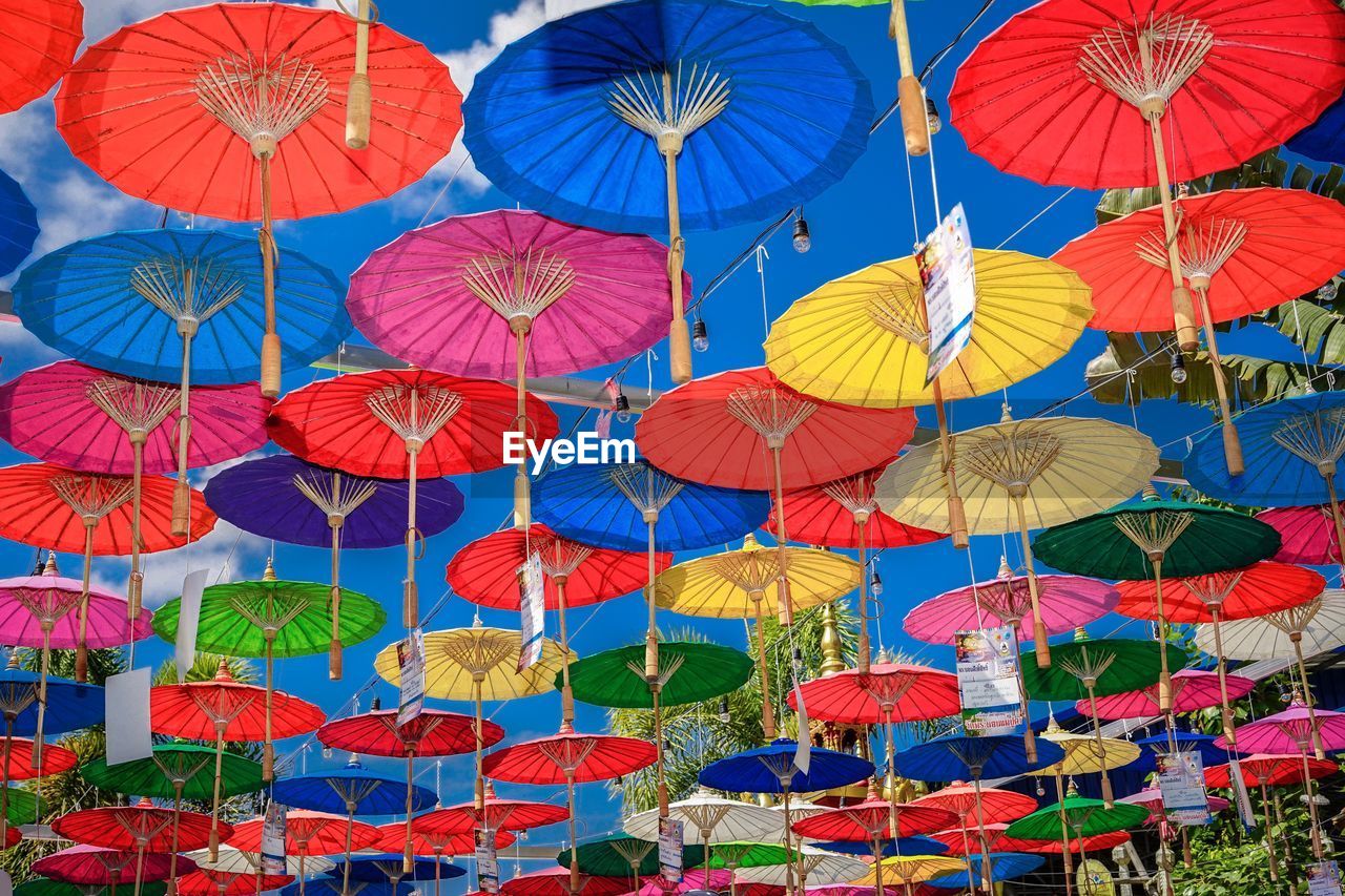 LOW ANGLE VIEW OF MULTI COLORED UMBRELLAS HANGING IN TRADITIONAL