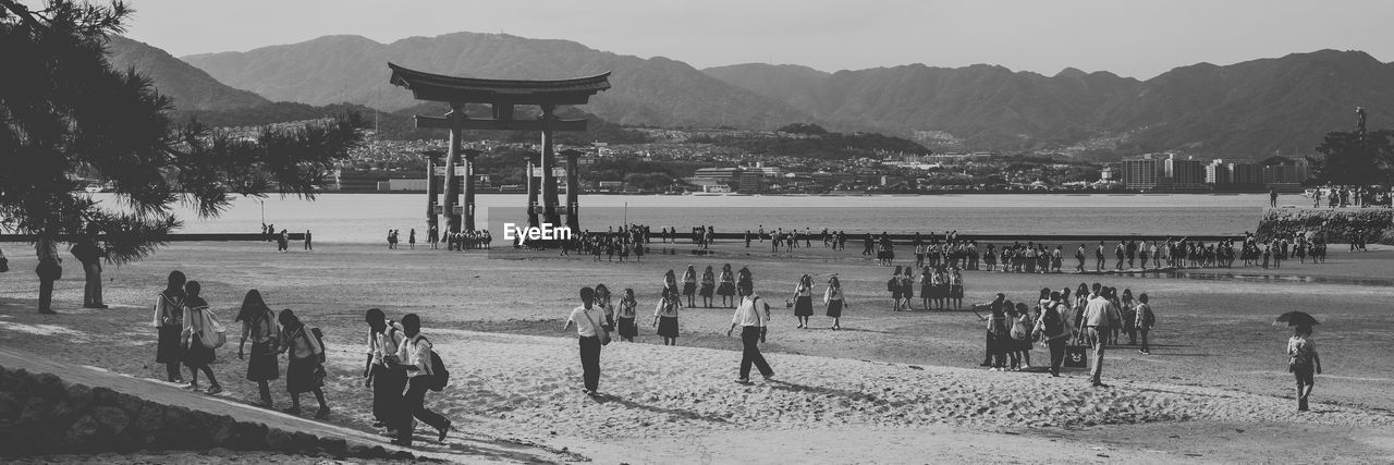 PEOPLE ON BEACH AGAINST MOUNTAIN RANGE