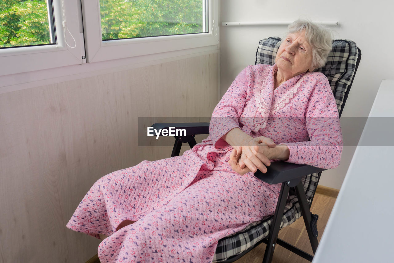 MIDSECTION OF WOMAN SITTING ON BENCH AT HOME