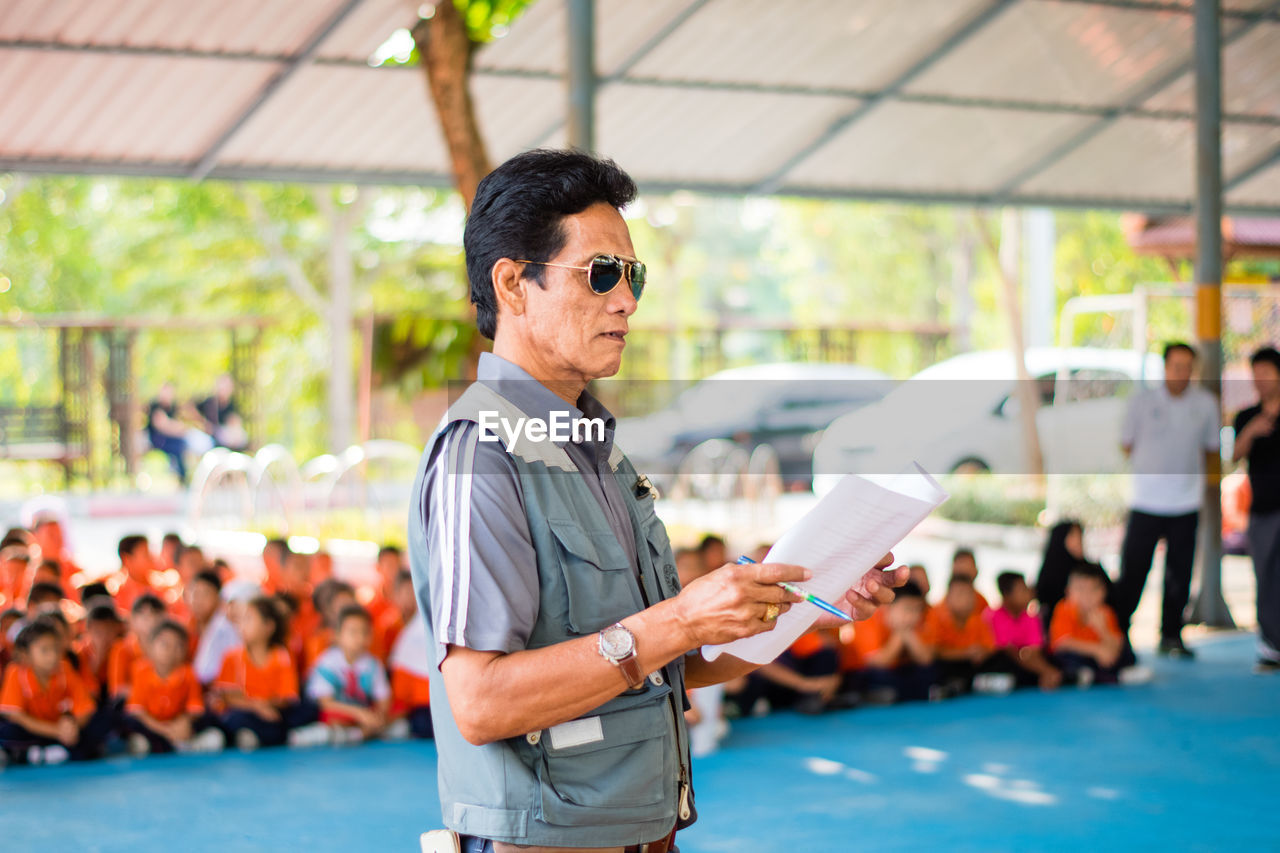 Teacher holding paper while standing in school during training