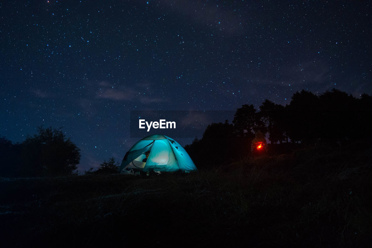 Illuminated tent on field against sky at night