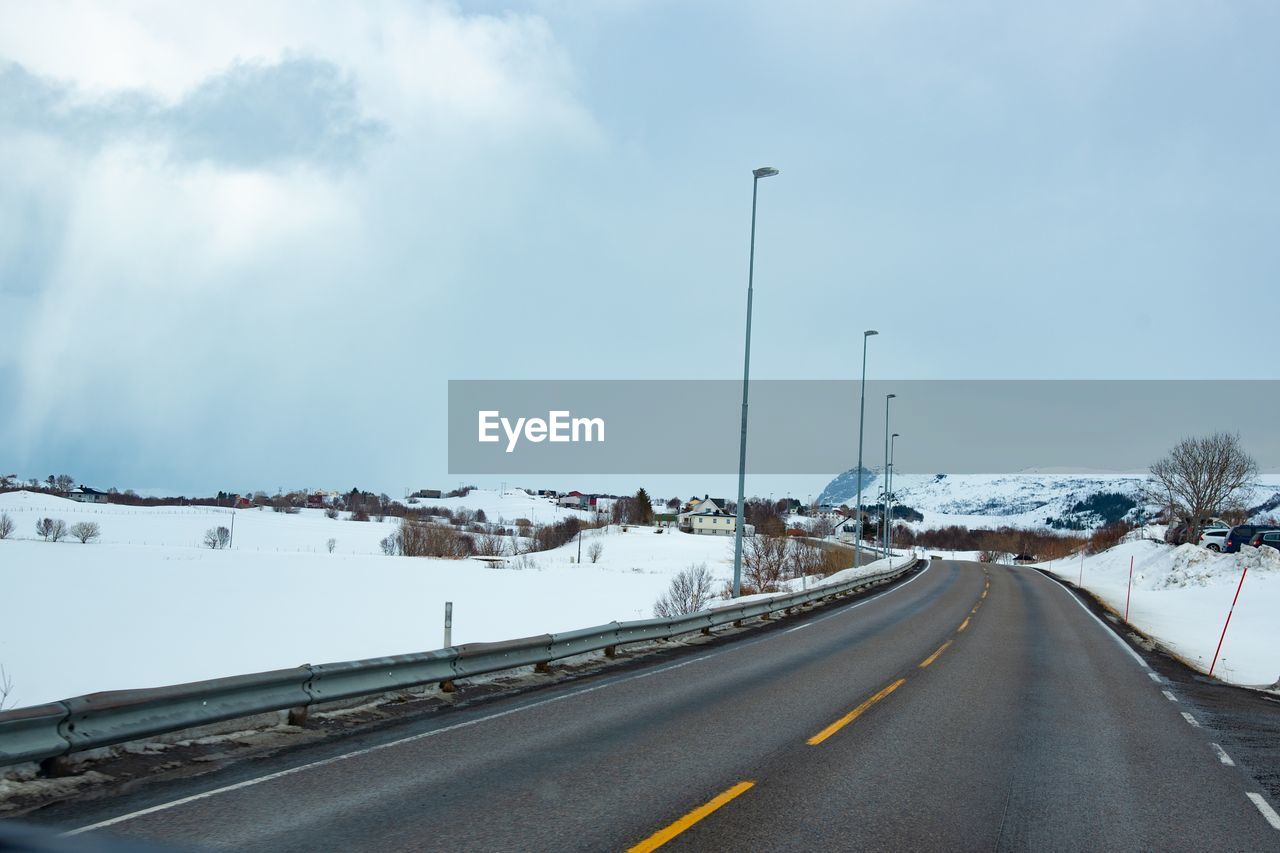 ROAD AMIDST SNOW COVERED LANDSCAPE