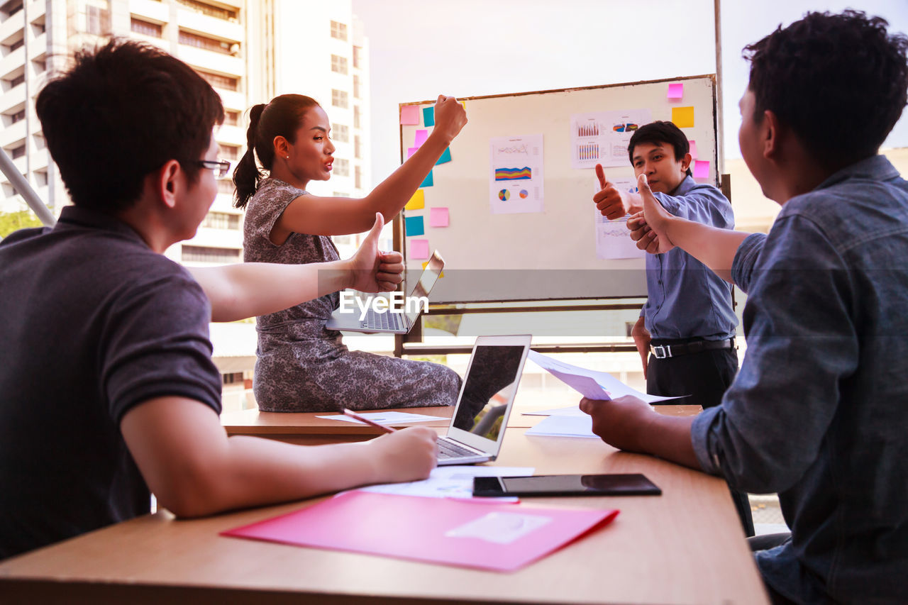 Colleagues discussing while gesturing during meeting in office