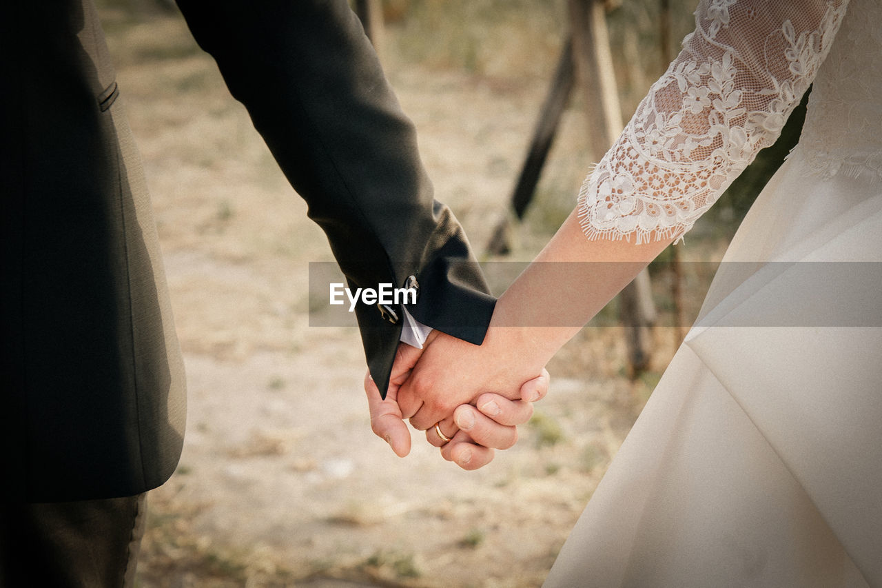 Midsection of newlywed couple holding hands