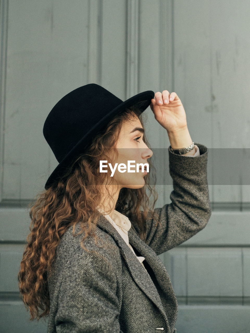 Side view of woman standing against wall