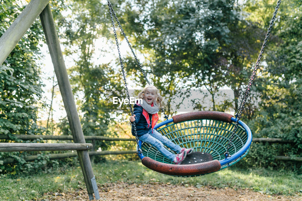 Full length of cute girl swinging at playground