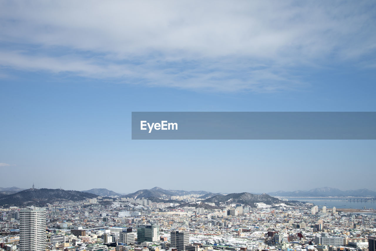 Aerial view of cityscape against blue sky