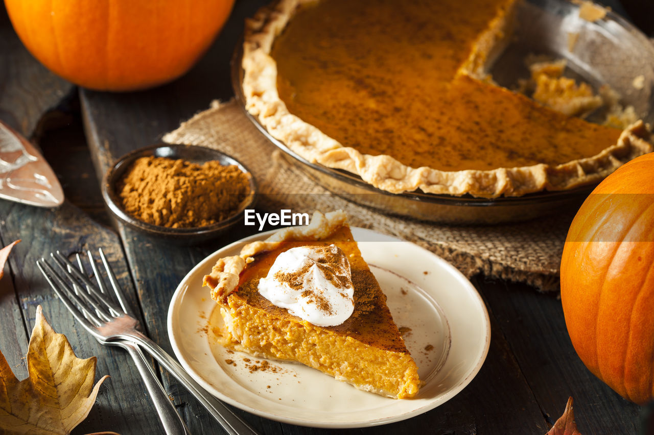 food and drink, food, pumpkin, sweet food, autumn, celebration, baked, pumpkin pie, sweet, produce, kitchen utensil, dessert, healthy eating, freshness, no people, eating utensil, dish, fruit, holiday, cake, spice, orange color, vegetable, rustic, indoors, wood, high angle view, wellbeing, plate