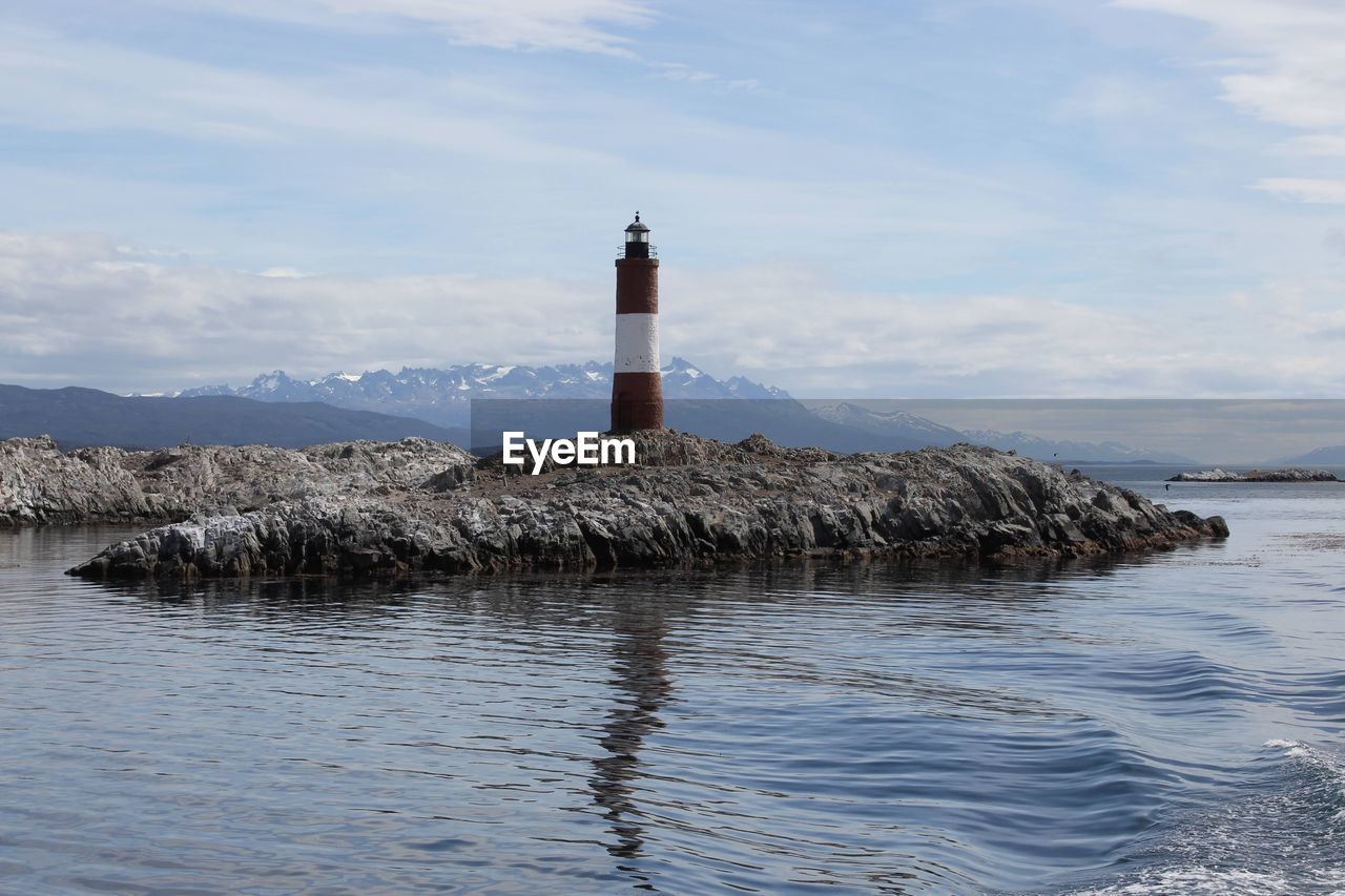 Lighthouse by sea against sky