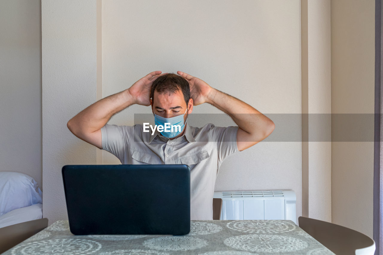 Frustrated man using laptop sitting at home