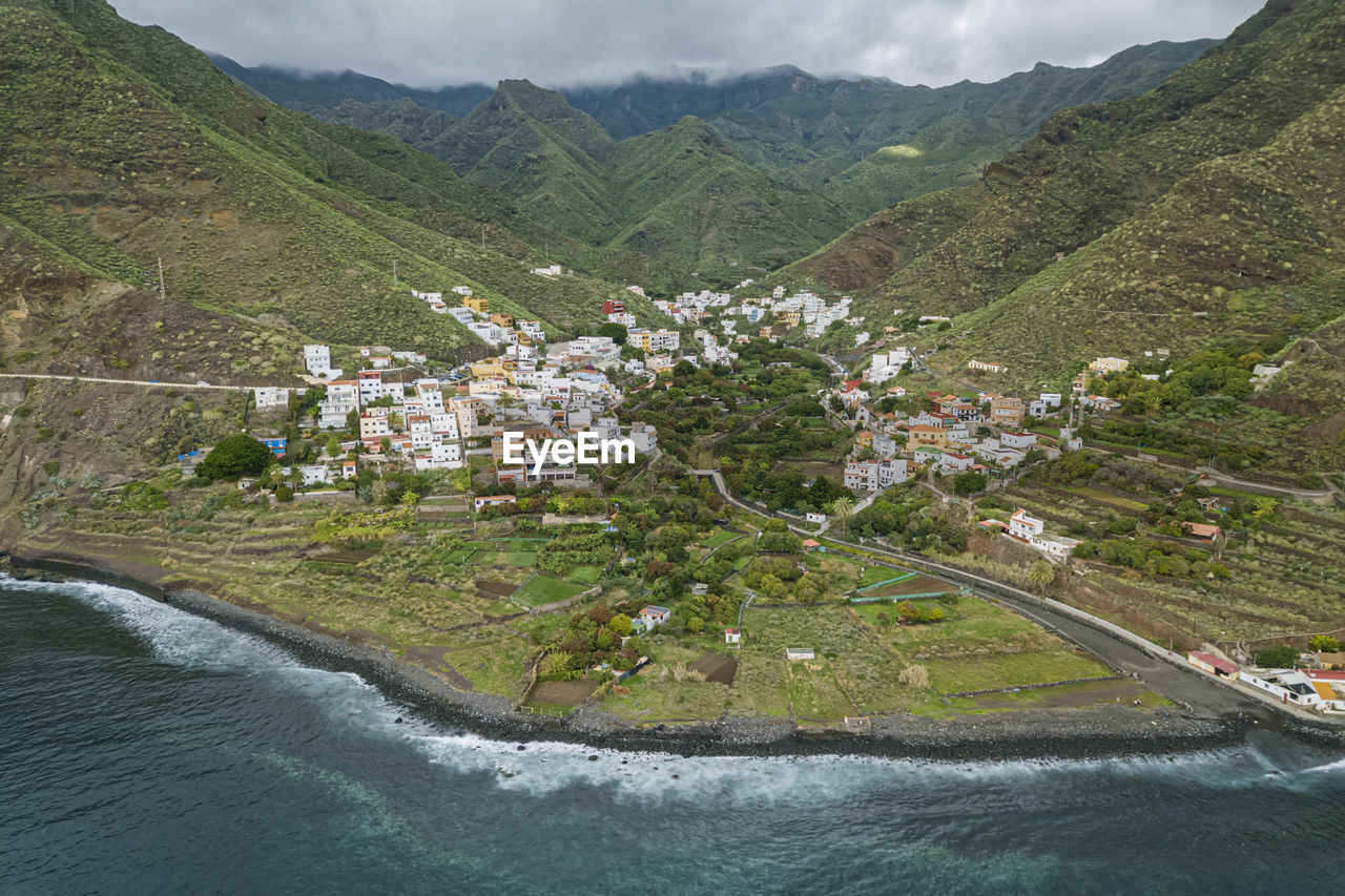 HIGH ANGLE VIEW OF TOWNSCAPE BY MOUNTAIN AGAINST SKY